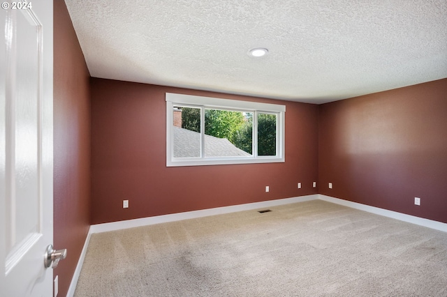 carpeted spare room featuring visible vents, a textured ceiling, and baseboards