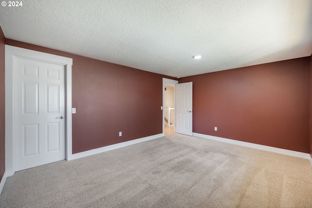 unfurnished room with a textured ceiling, baseboards, and carpet flooring