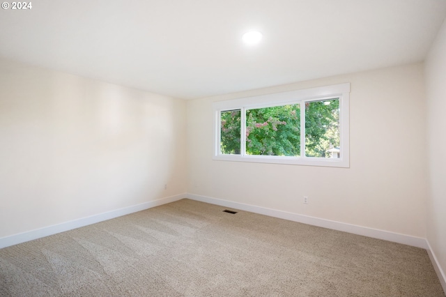 spare room with carpet flooring, visible vents, and baseboards