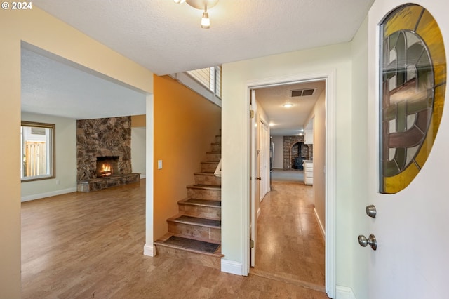 staircase featuring a fireplace, a textured ceiling, and hardwood / wood-style flooring