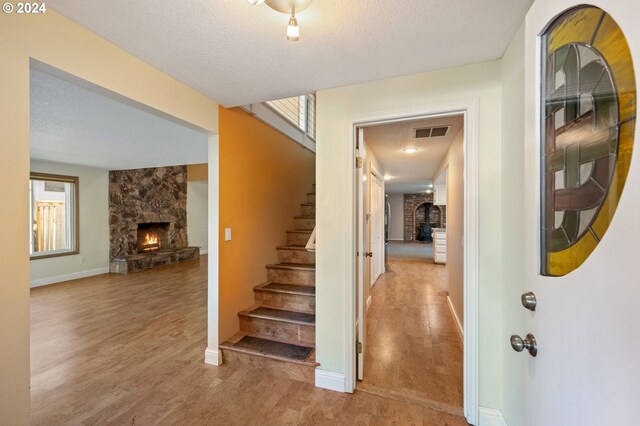 dining room with a stone fireplace, hardwood / wood-style floors, and a textured ceiling