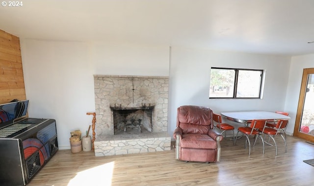 living room with a stone fireplace and light hardwood / wood-style flooring