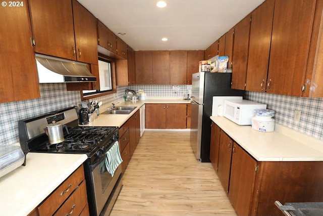 kitchen featuring decorative backsplash, appliances with stainless steel finishes, and light hardwood / wood-style flooring