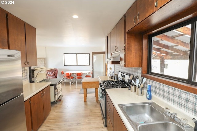 kitchen with tasteful backsplash, sink, light hardwood / wood-style flooring, and appliances with stainless steel finishes