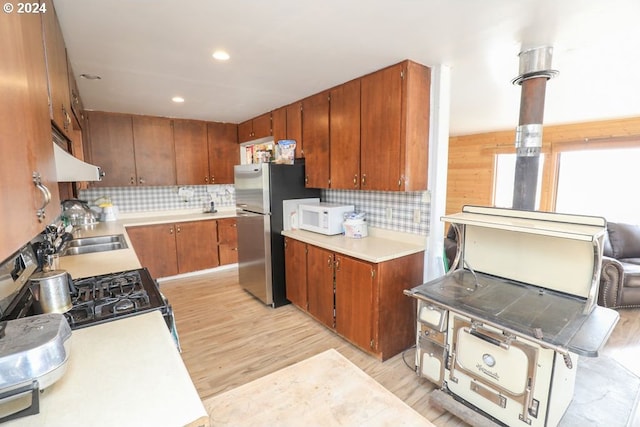 kitchen with decorative backsplash, light wood-type flooring, and sink