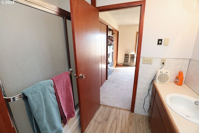 bathroom with hardwood / wood-style floors, vanity, and tile walls