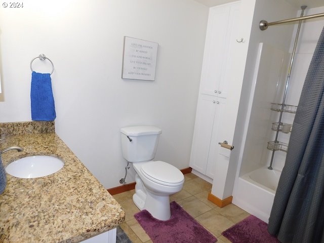 full bathroom with tile patterned floors, vanity, shower / bathtub combination with curtain, and toilet