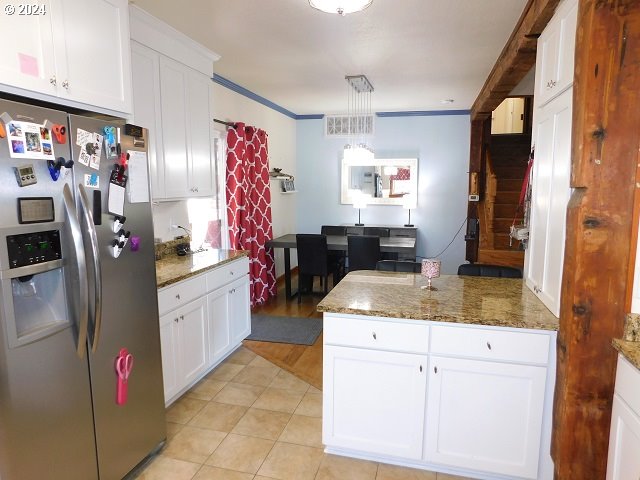 kitchen featuring white cabinets, crown molding, stainless steel refrigerator with ice dispenser, and hanging light fixtures