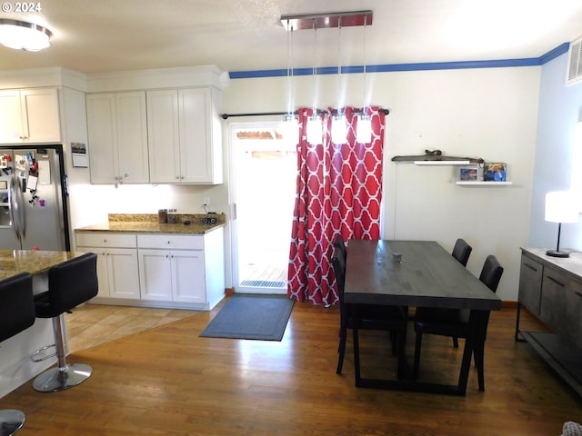 kitchen with white cabinets, stainless steel fridge, dark hardwood / wood-style flooring, and dark stone counters