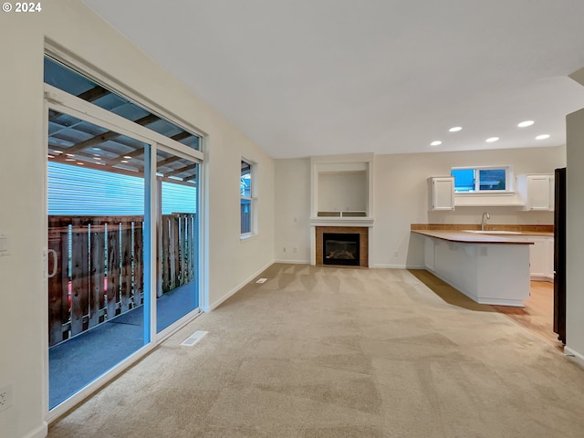 unfurnished living room featuring light colored carpet and sink