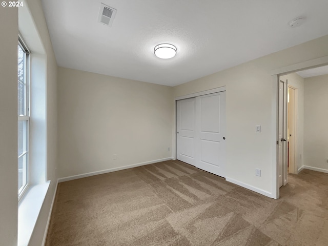 unfurnished bedroom with carpet flooring, a closet, and multiple windows