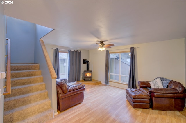 living room featuring ceiling fan, light hardwood / wood-style floors, and a wood stove