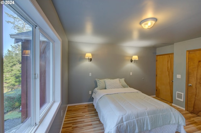 bedroom featuring light hardwood / wood-style floors, access to exterior, and multiple windows