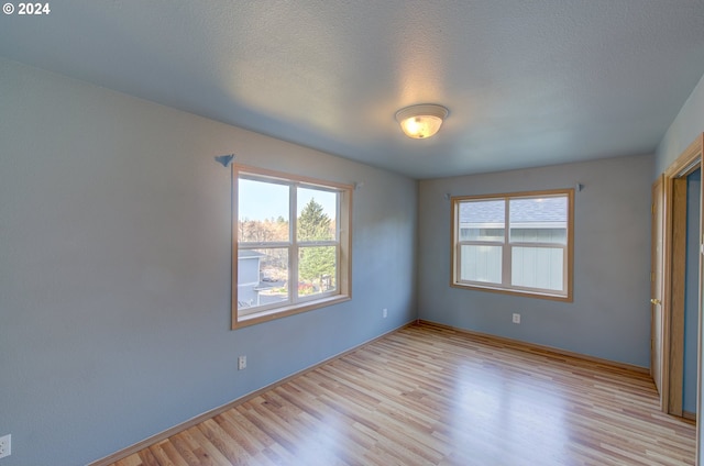 unfurnished bedroom with light wood-type flooring and a textured ceiling