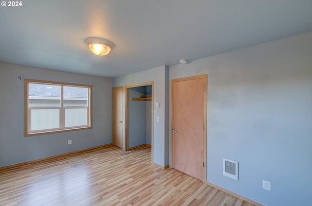 unfurnished bedroom with a closet and light wood-type flooring