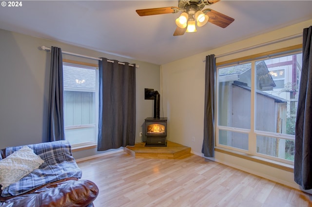 sitting room featuring light hardwood / wood-style flooring, ceiling fan, a healthy amount of sunlight, and a wood stove