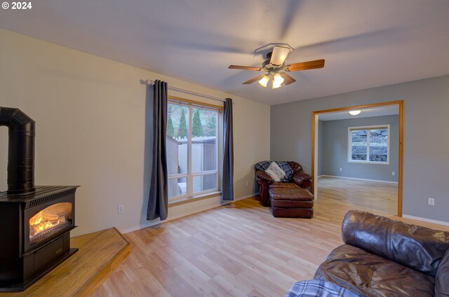 living room featuring ceiling fan, light wood-type flooring, and a wood stove