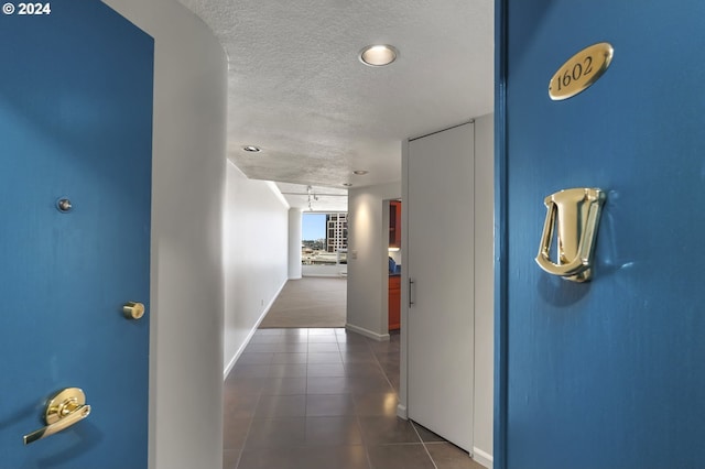 hallway with dark tile floors and a textured ceiling