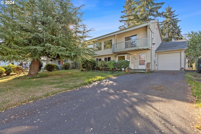 view of front of house featuring a garage, a balcony, and a front yard