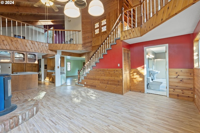 interior space with beam ceiling, wood walls, hardwood / wood-style floors, and high vaulted ceiling