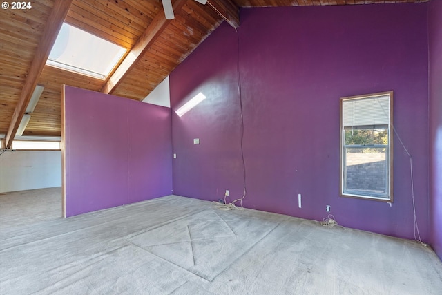 additional living space with beam ceiling, a skylight, ceiling fan, high vaulted ceiling, and light colored carpet