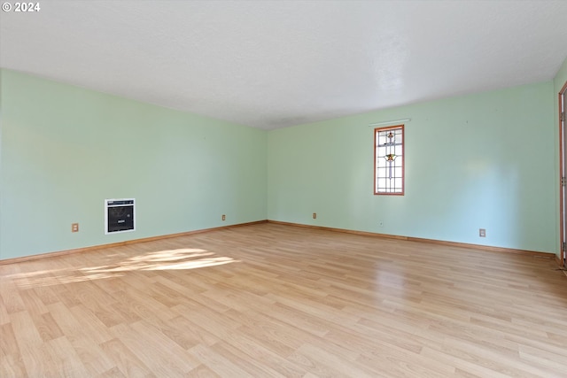 empty room featuring a textured ceiling, heating unit, and light hardwood / wood-style flooring