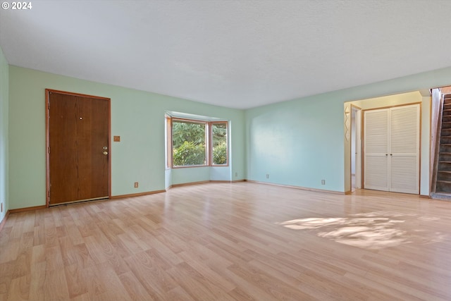 unfurnished room with a textured ceiling and light wood-type flooring