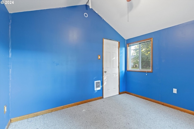 carpeted spare room featuring heating unit, vaulted ceiling, and ceiling fan