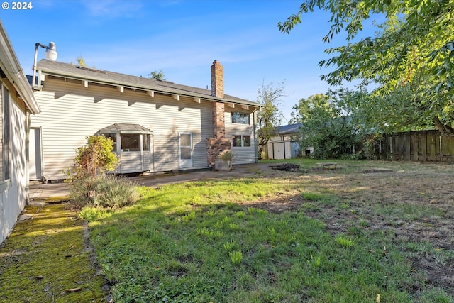 rear view of house with a storage unit and a yard