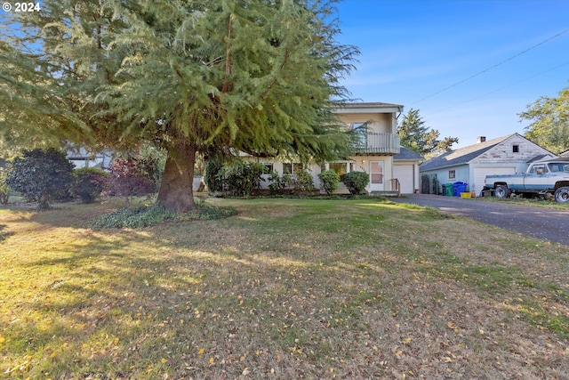 obstructed view of property featuring a garage, a balcony, and a front lawn