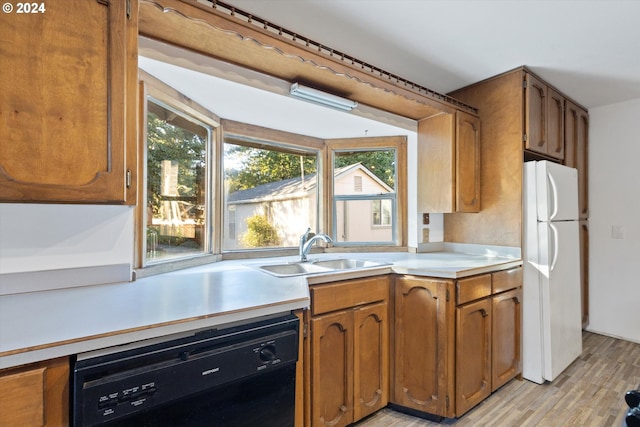 kitchen featuring sink, black dishwasher, white refrigerator, light hardwood / wood-style floors, and vaulted ceiling