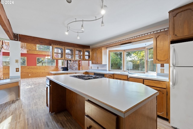 kitchen featuring wood-type flooring, white refrigerator, a center island, and black gas cooktop