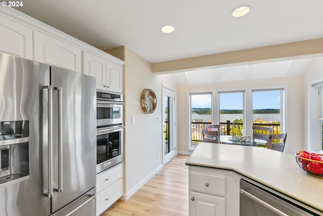 kitchen with white cabinets, lofted ceiling with beams, a water view, and stainless steel appliances