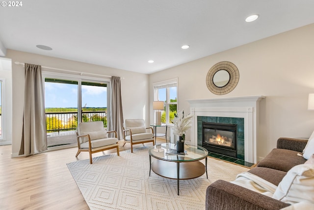 living room with recessed lighting, a tiled fireplace, and wood finished floors