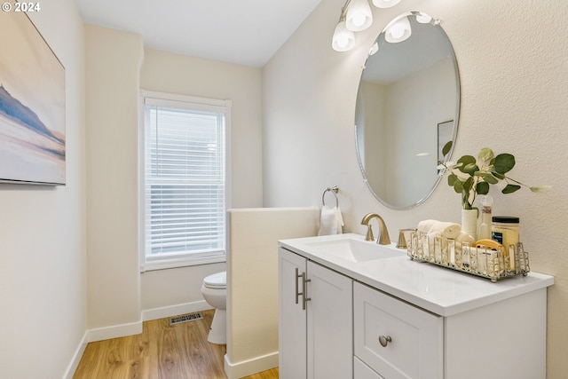 bathroom featuring toilet, plenty of natural light, visible vents, and wood finished floors