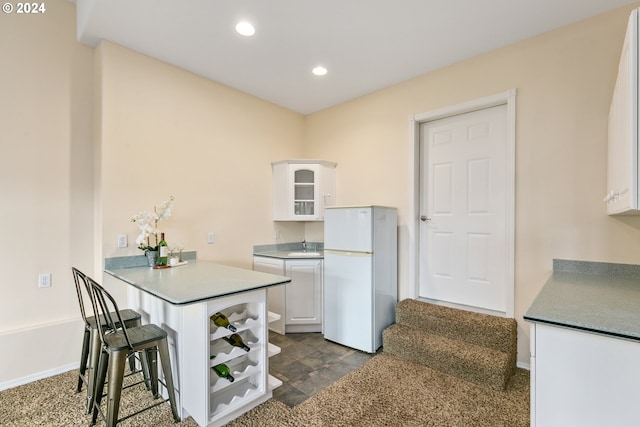 kitchen featuring freestanding refrigerator, white cabinets, a peninsula, and recessed lighting