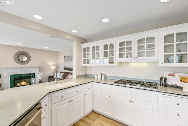 kitchen featuring recessed lighting, a premium fireplace, a sink, appliances with stainless steel finishes, and glass insert cabinets