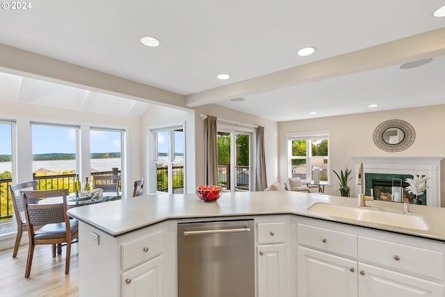 kitchen featuring a water view, sink, light hardwood / wood-style flooring, stainless steel dishwasher, and white cabinetry