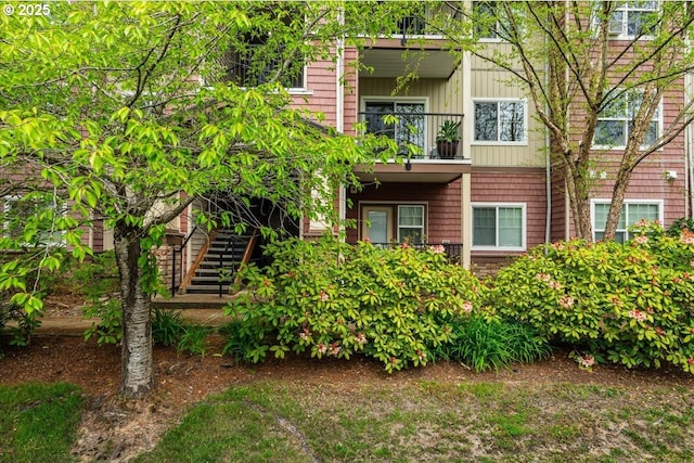 view of front of house with board and batten siding, stairs, and a balcony