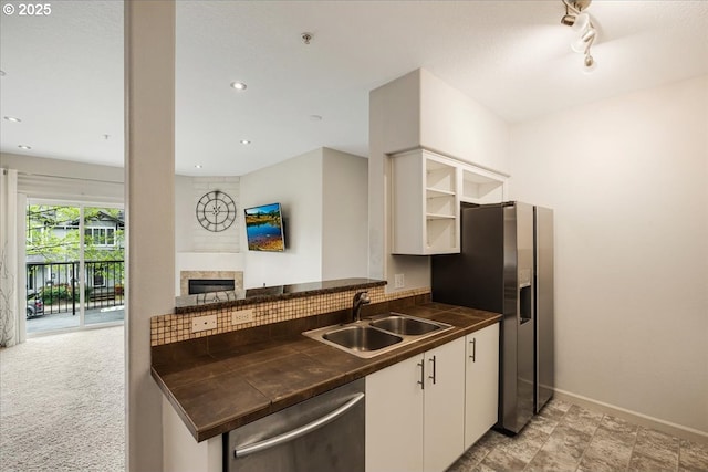 kitchen featuring stainless steel appliances, a sink, dark countertops, baseboards, and white cabinetry