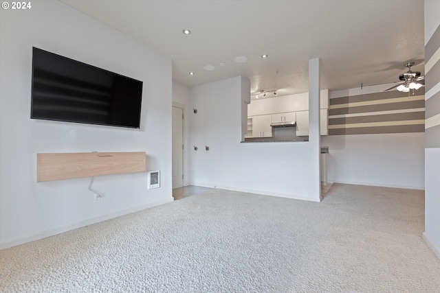 unfurnished living room with light colored carpet and ceiling fan