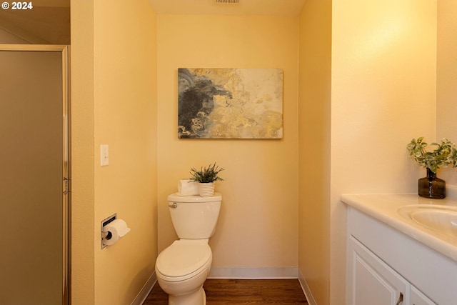 bathroom with walk in shower, wood-type flooring, vanity, and toilet