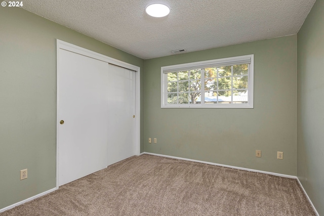 unfurnished bedroom featuring carpet, a textured ceiling, and a closet