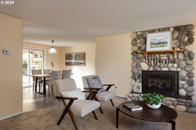 living room with a stone fireplace, a textured ceiling, and carpet