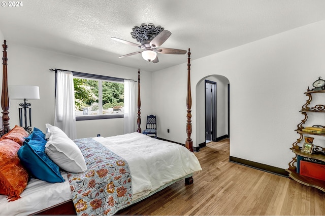 bedroom featuring light wood-type flooring, ceiling fan, and a textured ceiling