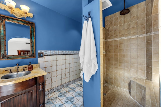 bathroom featuring tile walls, a tile shower, vanity, and tile patterned flooring