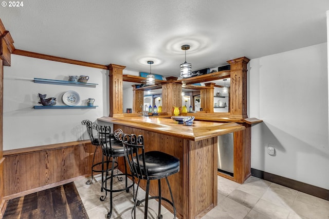 bar with butcher block countertops, a textured ceiling, wooden walls, and pendant lighting