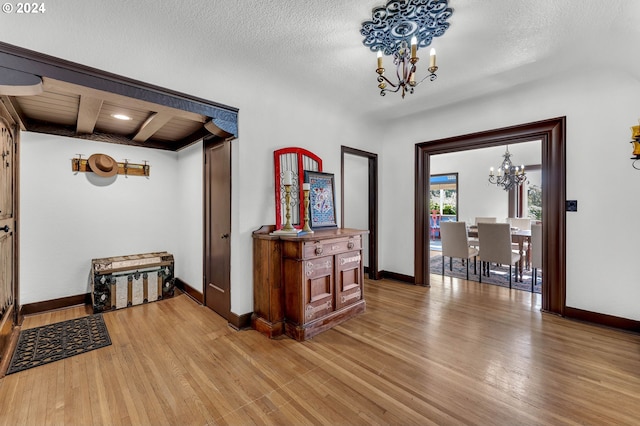 hall featuring wood-type flooring, a chandelier, and a textured ceiling