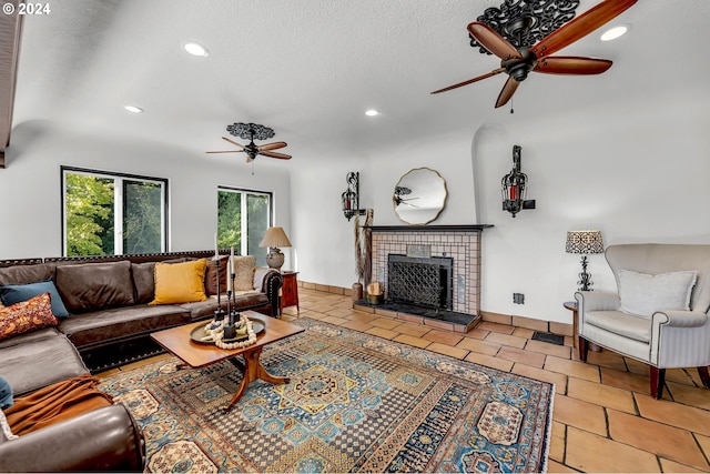 living room with a textured ceiling, tile patterned flooring, a fireplace, and ceiling fan