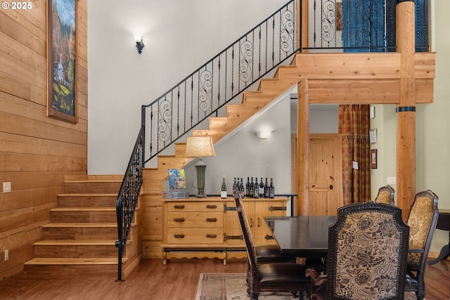 stairs with hardwood / wood-style flooring, a high ceiling, and wooden walls